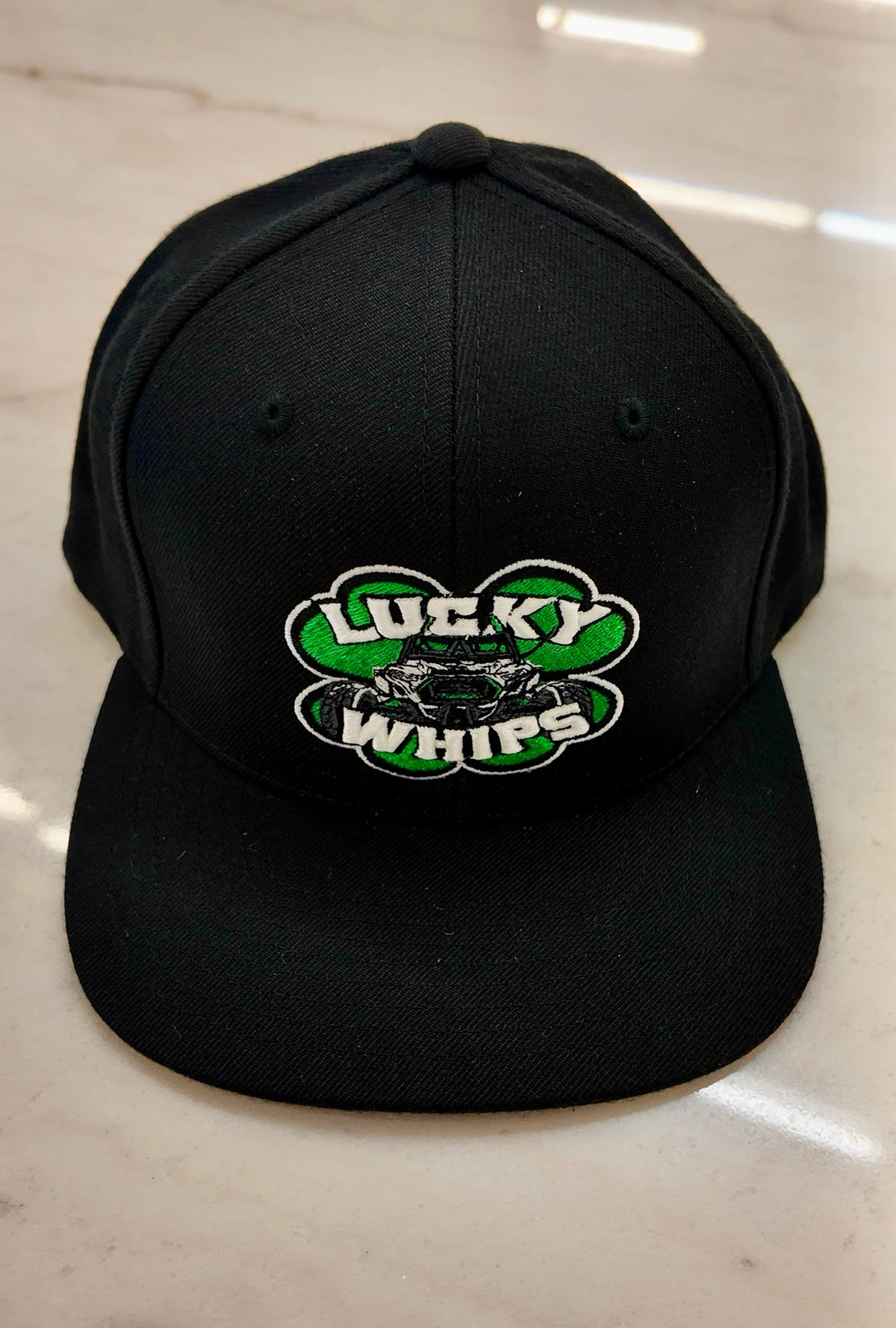 Lucky Whips classic flat bill hat with a structured crown and curved brim, shown in a neutral color on a plain background.