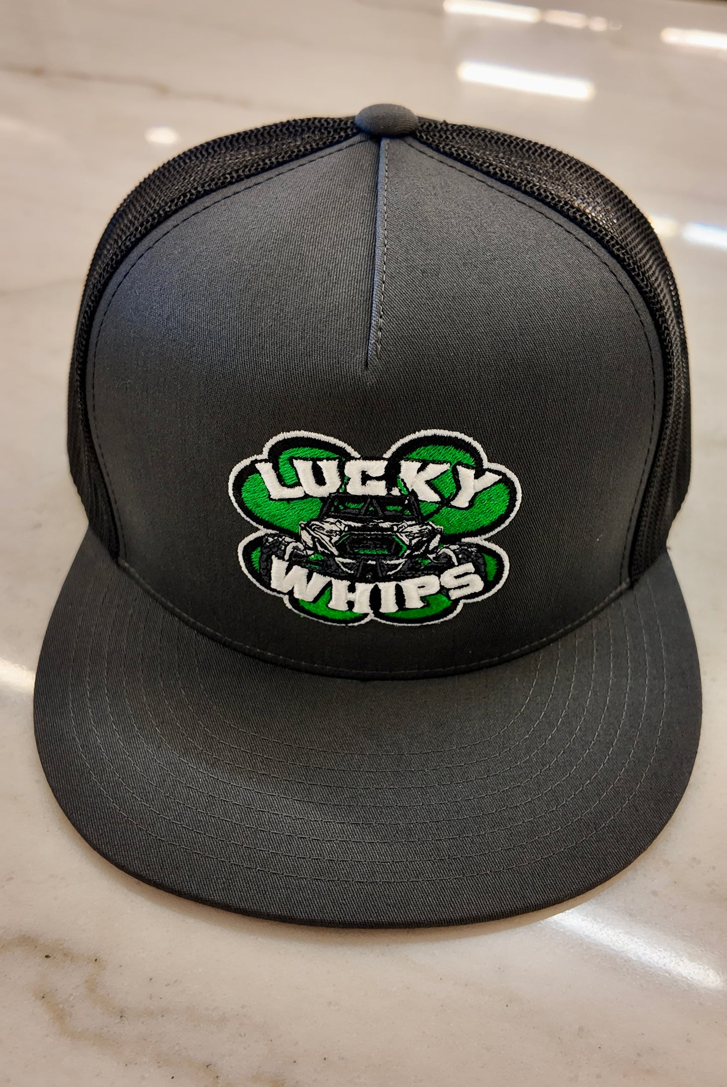 Charcoal Lucky Whips Trucker Flat Bill Hat with adjustable snapback and mesh back for a casual, stylish look.